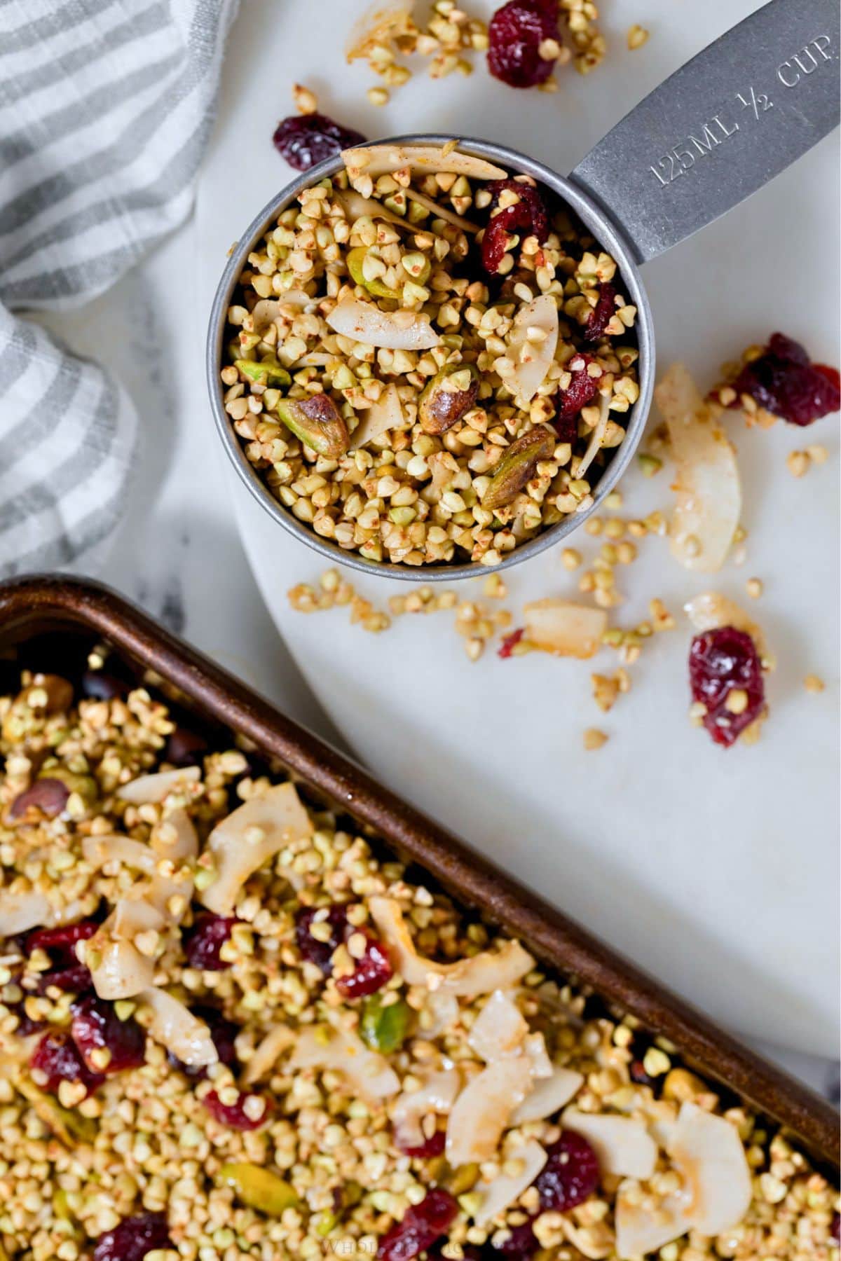 buckwheat granola in measuring cup and on baking tray.