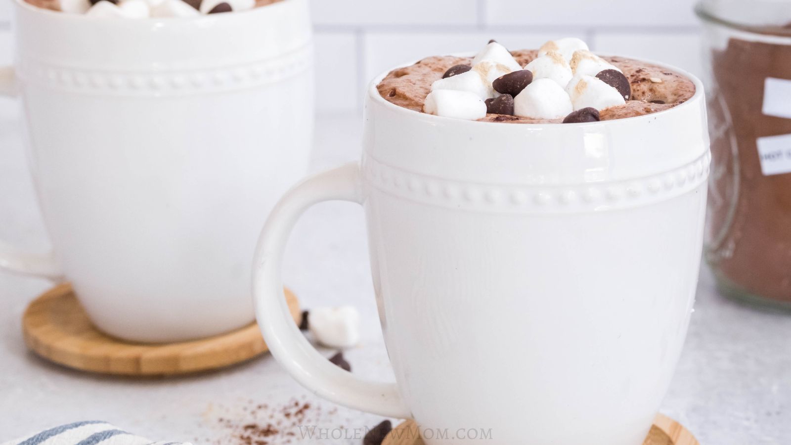 healthy hot chocolate in white mugs with mini marshmallows and chocolate chips.