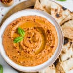 pizza hummus in white bowl with pita wedges
