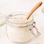 homemade oat flour in a jar with a wooden spoon