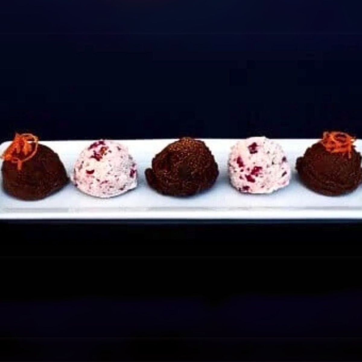 three varieties of coconut butter fat bombs on a white plate.
