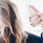 woman spraying homemade hairspray on her hair.