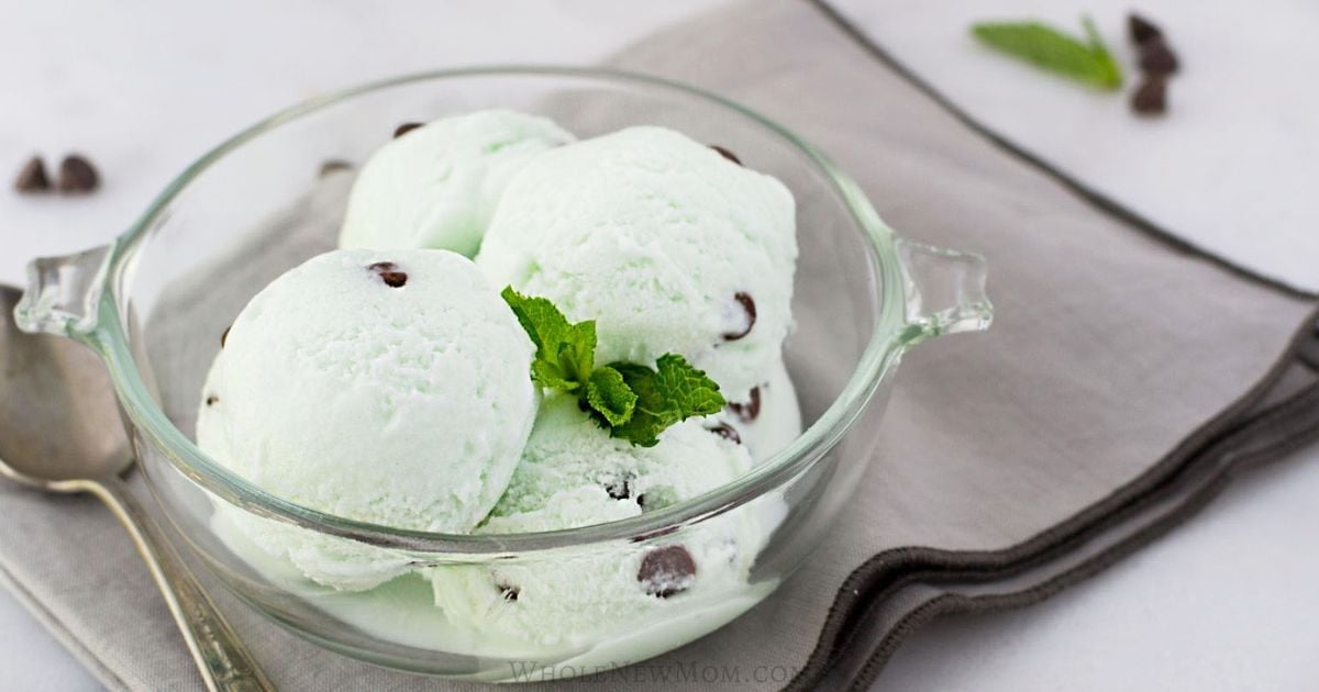 clear bowl full of scoops of mint chocolate chip ice cream topped with mint leaves.