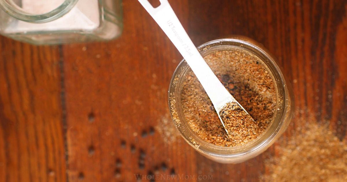 homemade chaat masala in glass jar with white spoon.