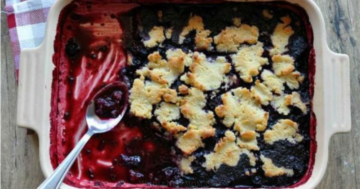 berry cobbler on a white baking dish with spoon.