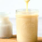 spoon dripping homemade dairy-free condensed milk into a mason jar.