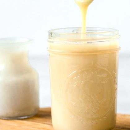 spoon dripping homemade dairy-free condensed milk into a mason jar.