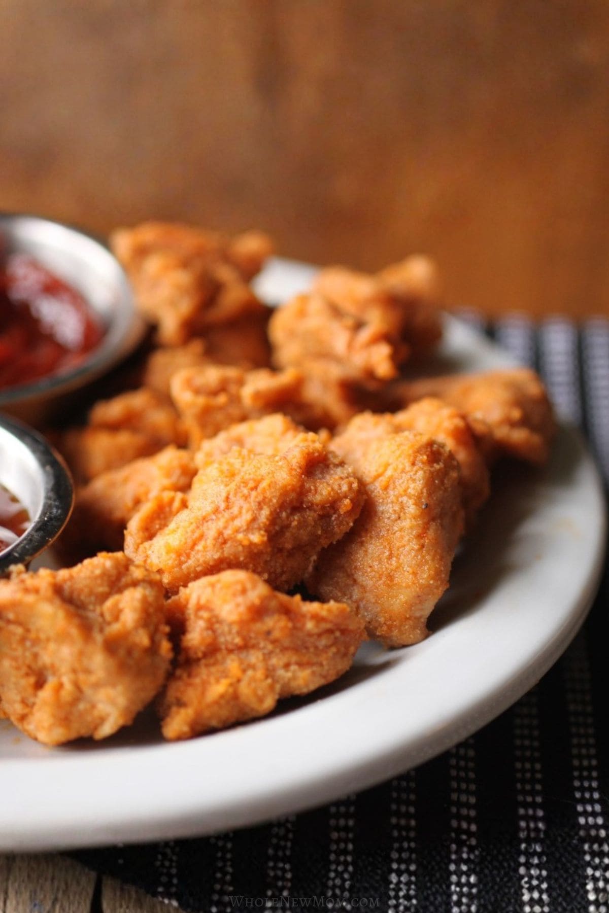 gluten-free chicken nuggets on white plate with bbq dipping sauce.
