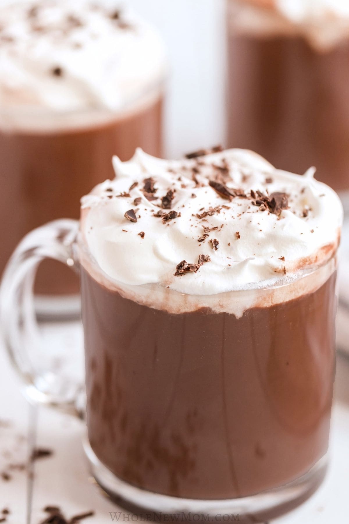 protein hot chocolate in glass mug with whipped cream and chocolate shavings.