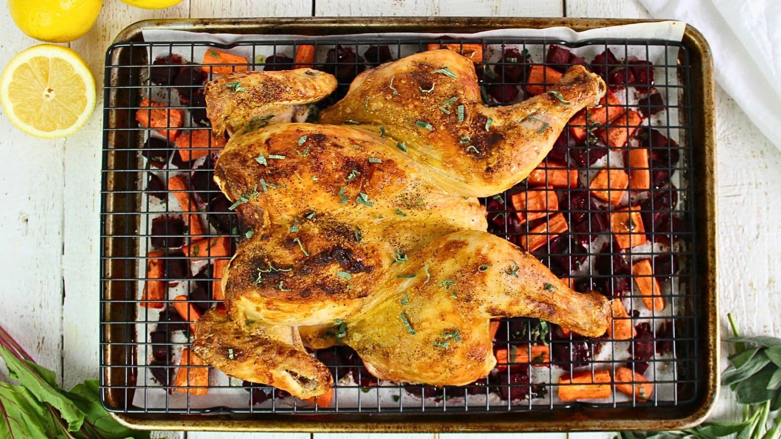 spatchcock chicken with roasted vegetables on baking pan