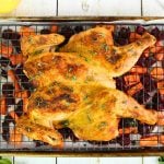 spatchcock chicken on rack over roasted vegetables.