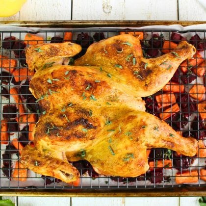 spatchcock chicken on rack over roasted vegetables.