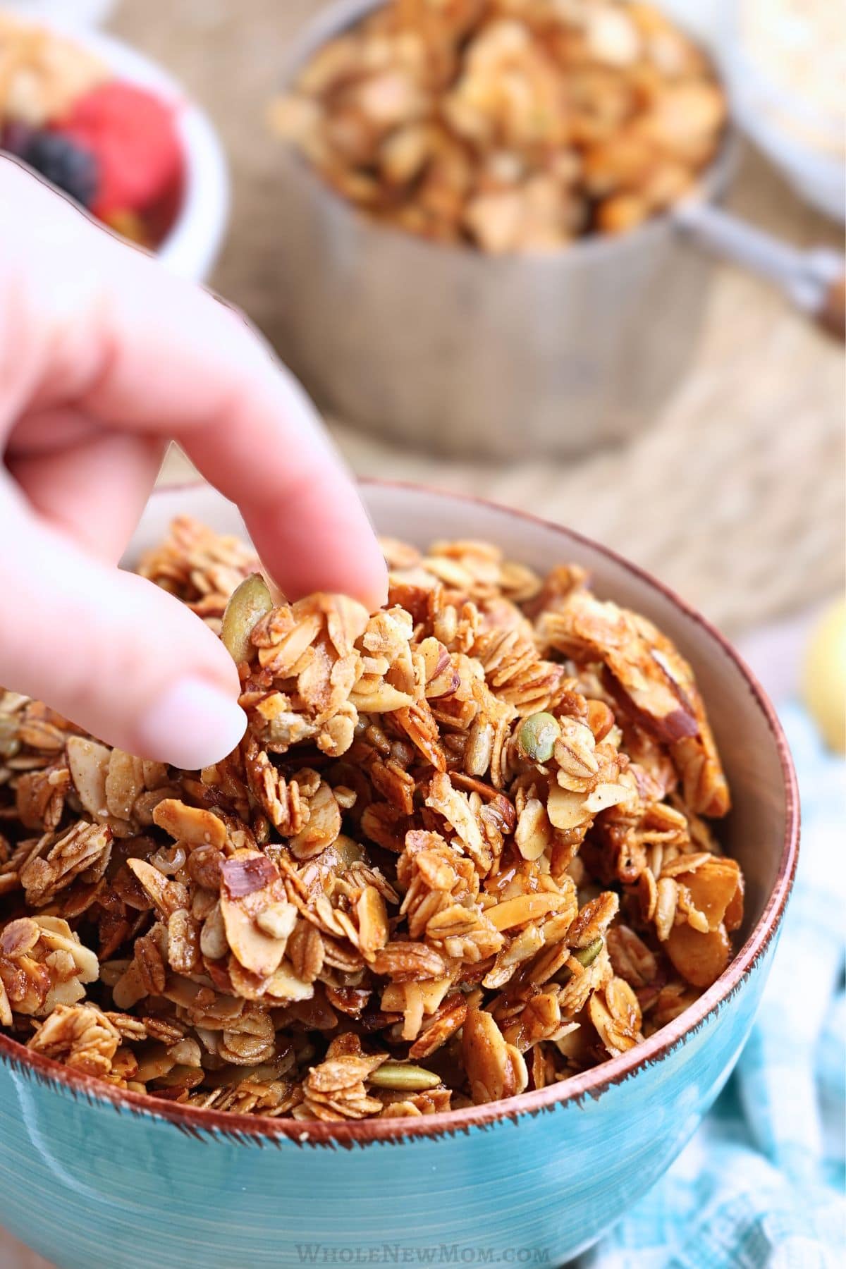 hand taking sugar-free granola out of a blue bowl.