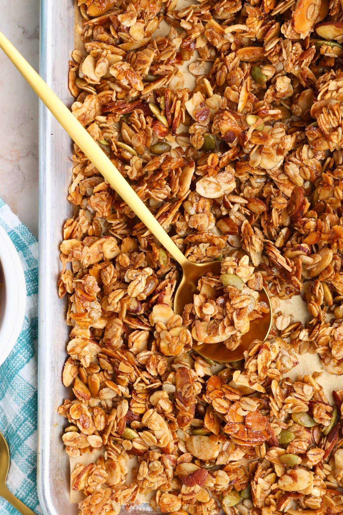 sugar-free granola in baking tray with gold spoon.