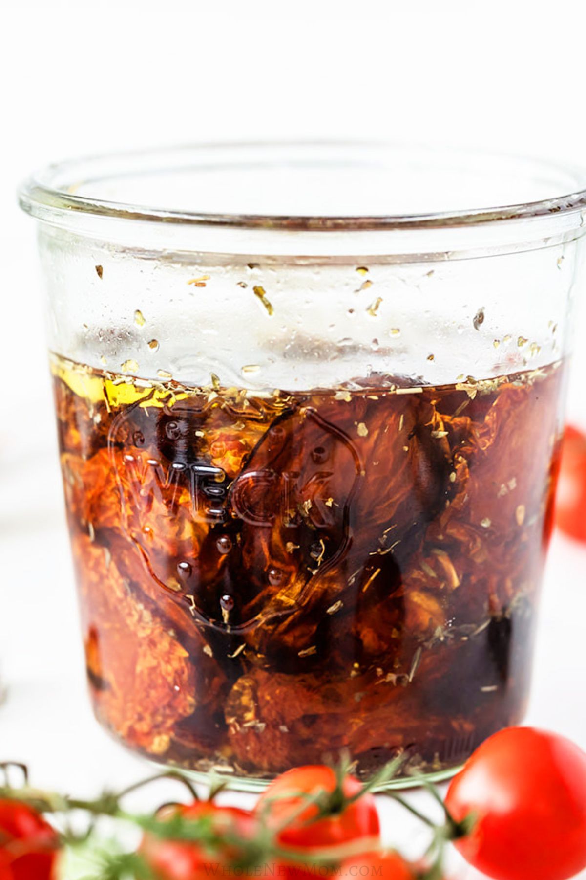 homemade sun-dried-tomatoes in jar with herbs and olive oil.