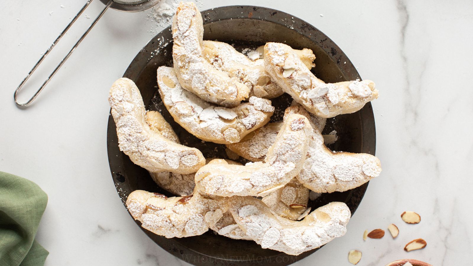 almond flour crescent cookies on black plate.