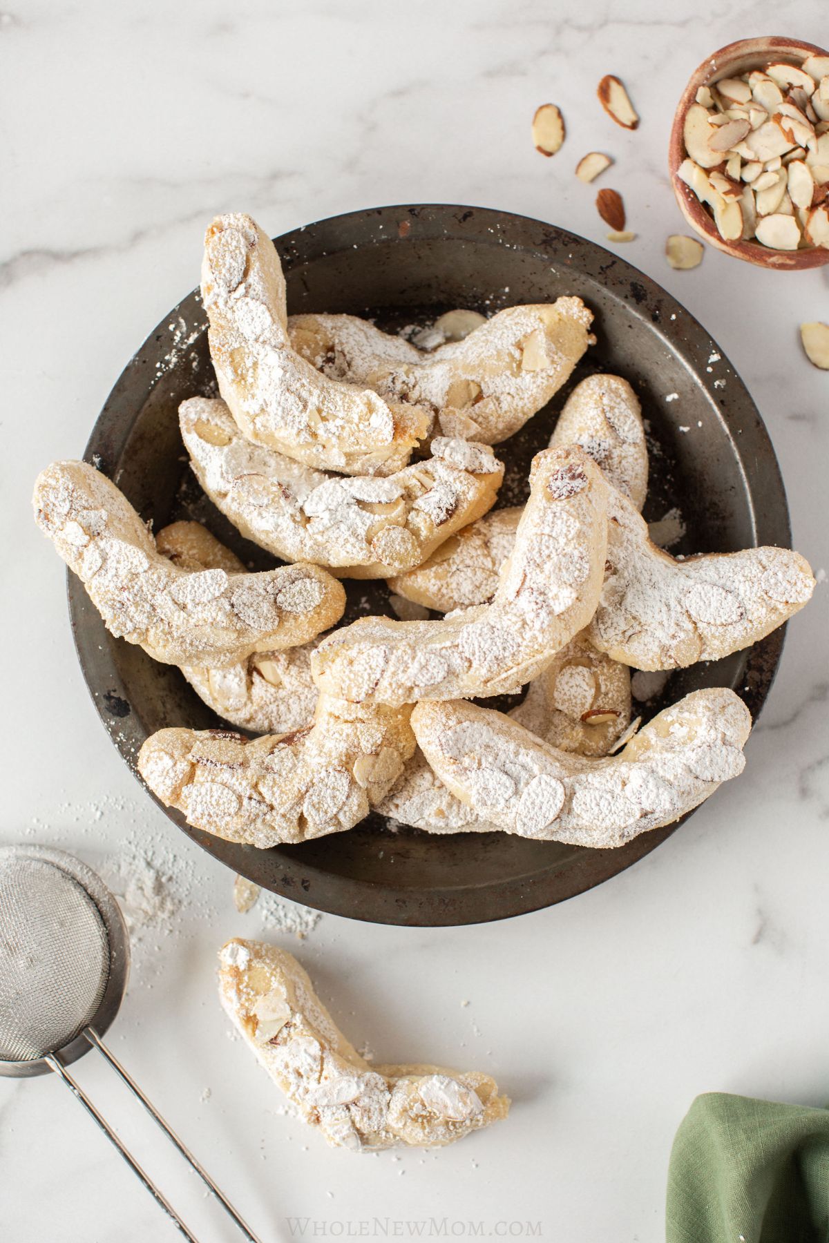 almond flour crescent cookies on black plate.