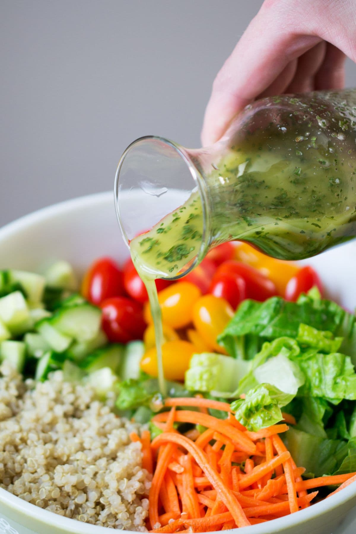 pouring lemon vinaigrette on garden quinoa salad.