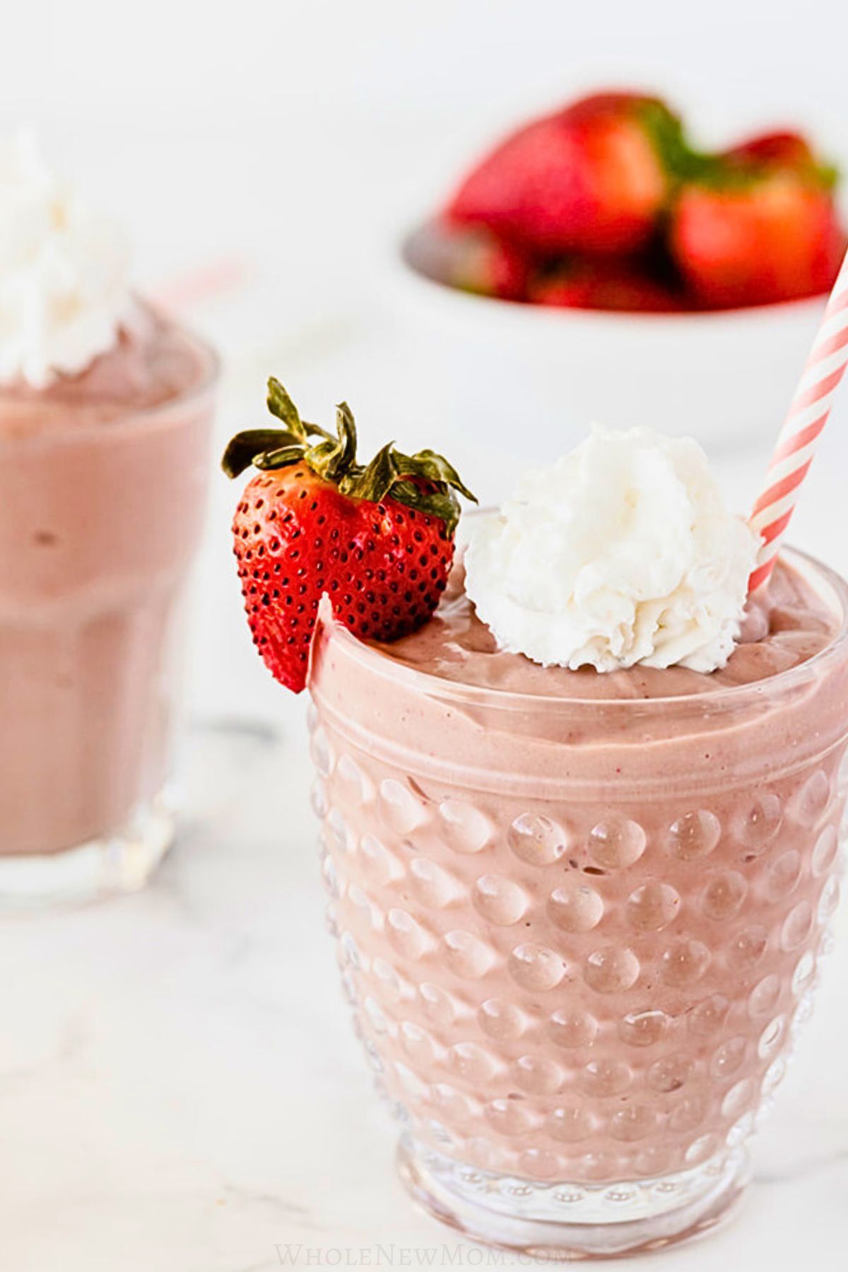 strawberry avocado smoothies with whipped cream in dessert glass.