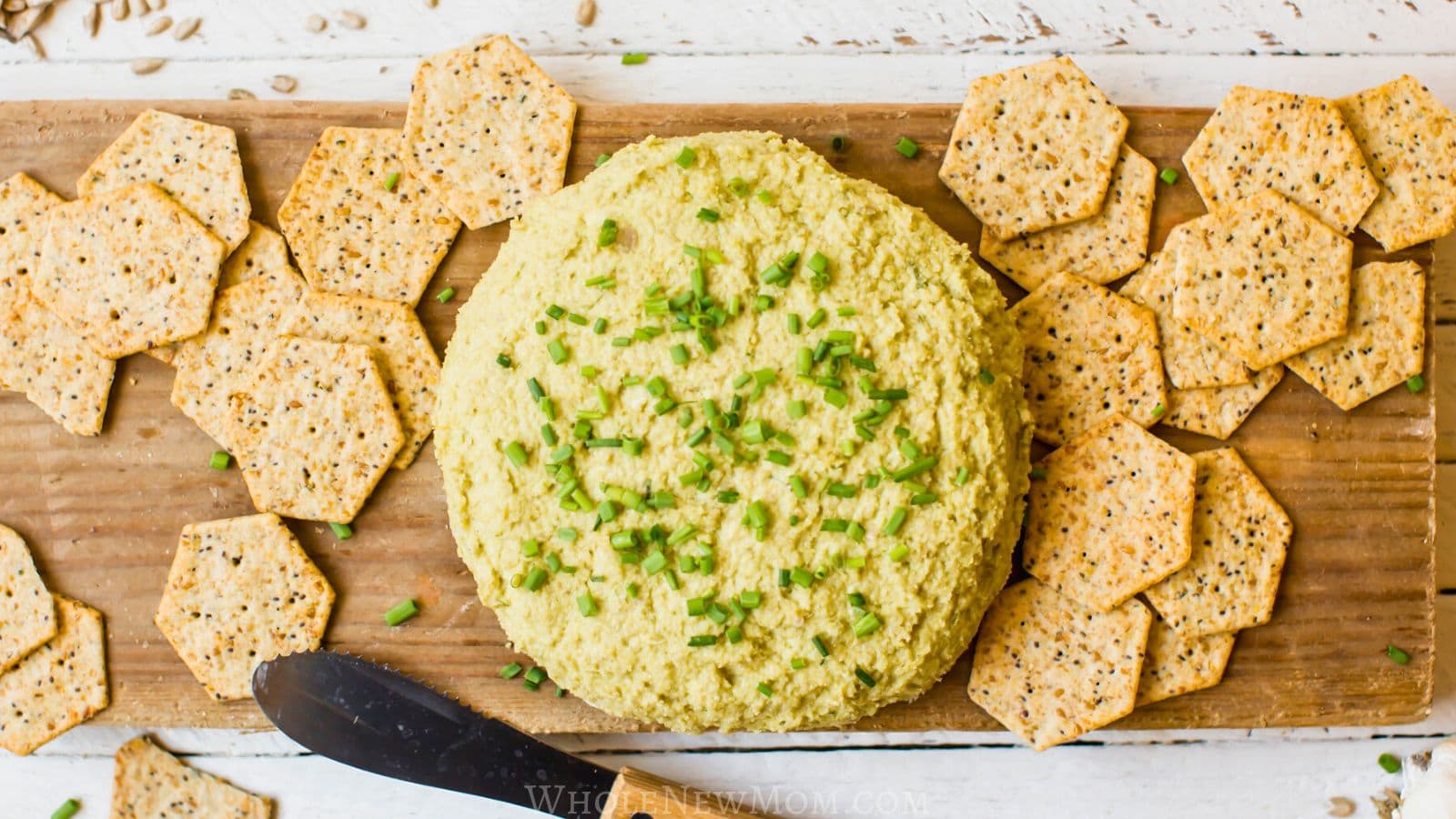 sunflower seed cheese with crackers on wood cutting board.