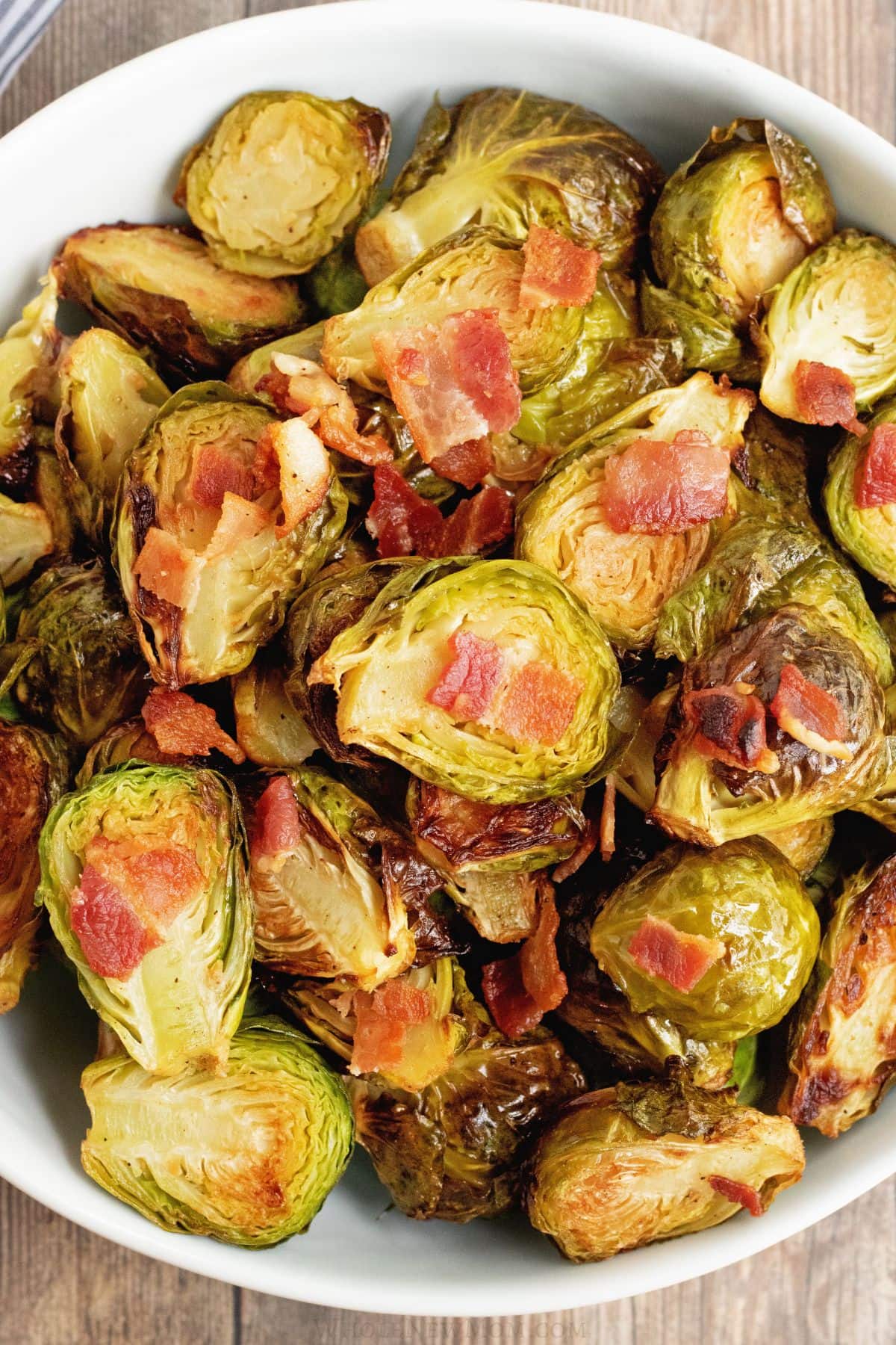 crispy roasted brussels sprouts with bacon in white bowl.
