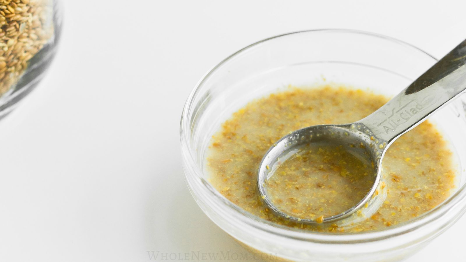 flax egg in small glass bowl with metal measuring spoon.