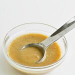 flax egg in small glass bowl with metal measuring spoon.