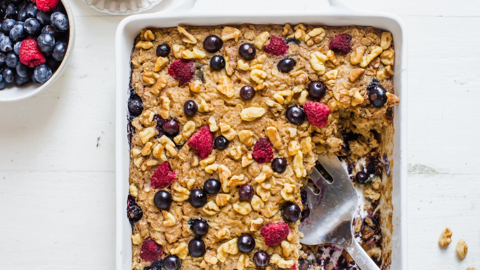 gluten free baked oatmeal in pan with berries and nuts.