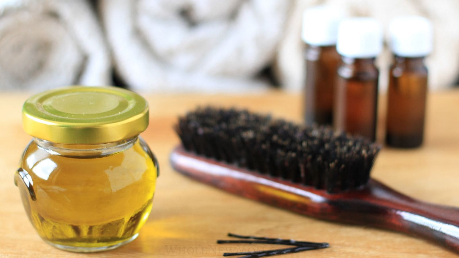 hair growth oil blend with brush, essential oils, and bobby pins on table.