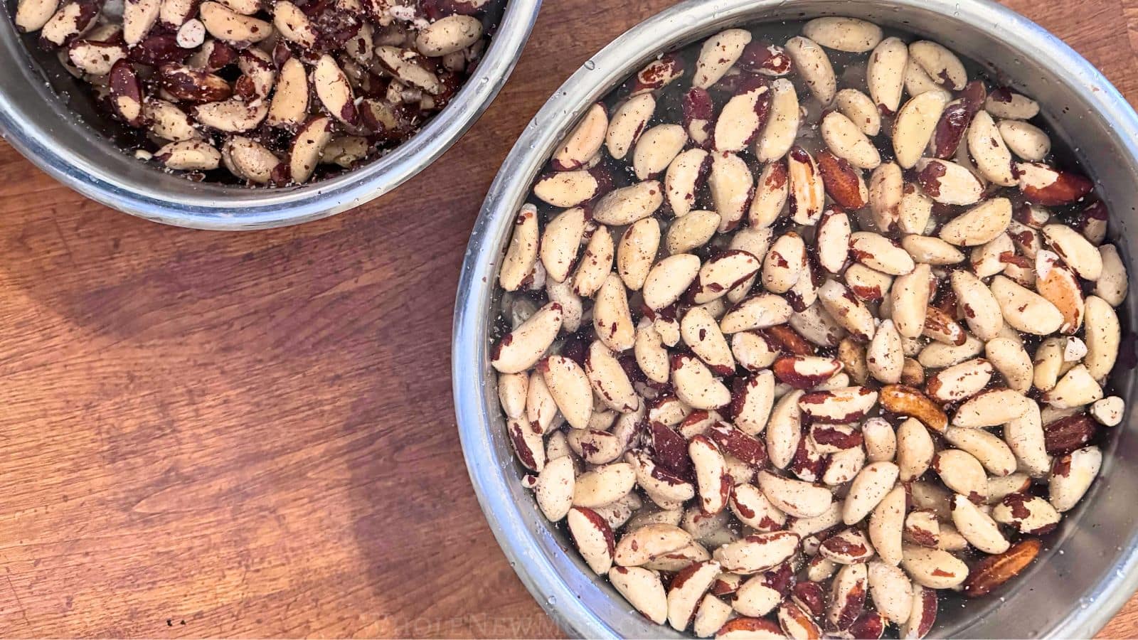 brazil nuts soaking in salt water in metal bowls.