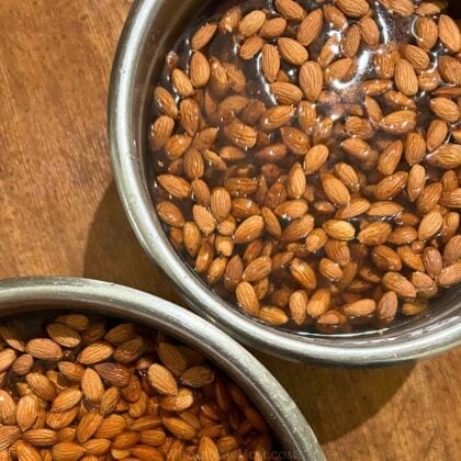 almonds soaking in salt water in metal bowls.