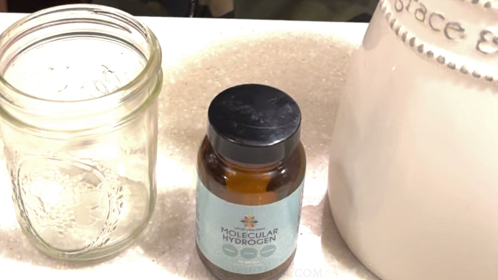 bottle of whole new mom's hydrogen tablets with glass and pitcher to show how to use hydrogen tabets.