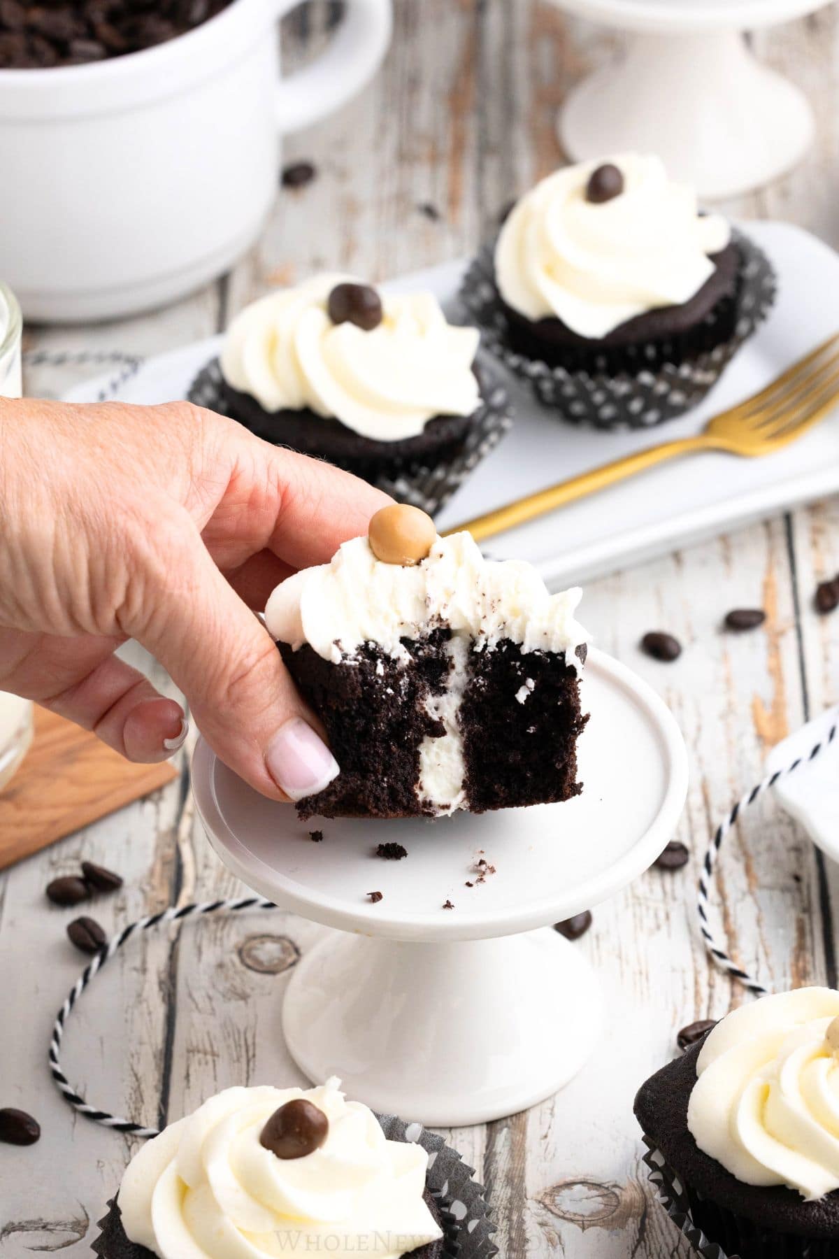 hand holding gluten free chocolate cupcake with cream filling.