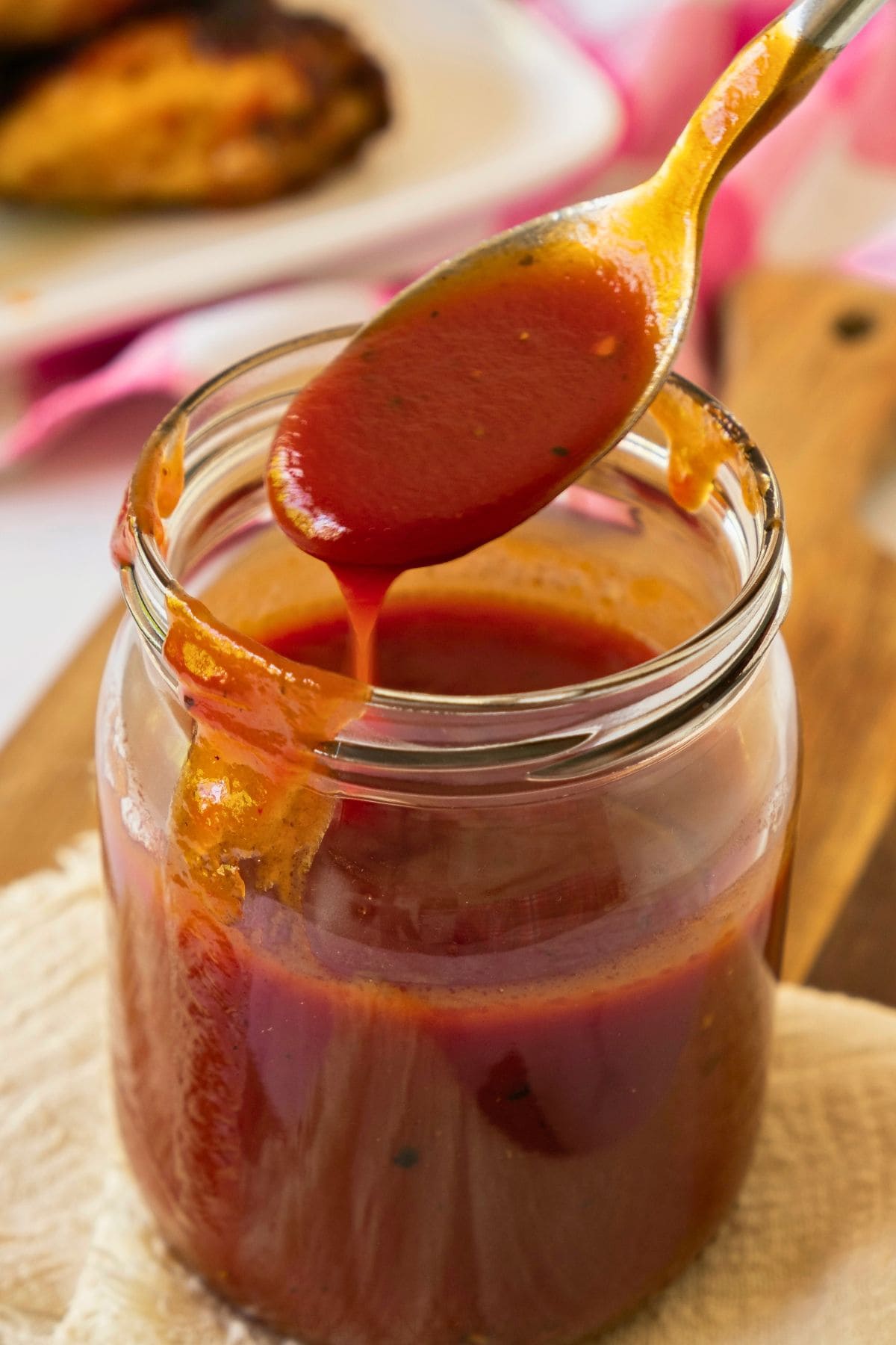 keto bbq sauce in glass jar with wooden spoon.
