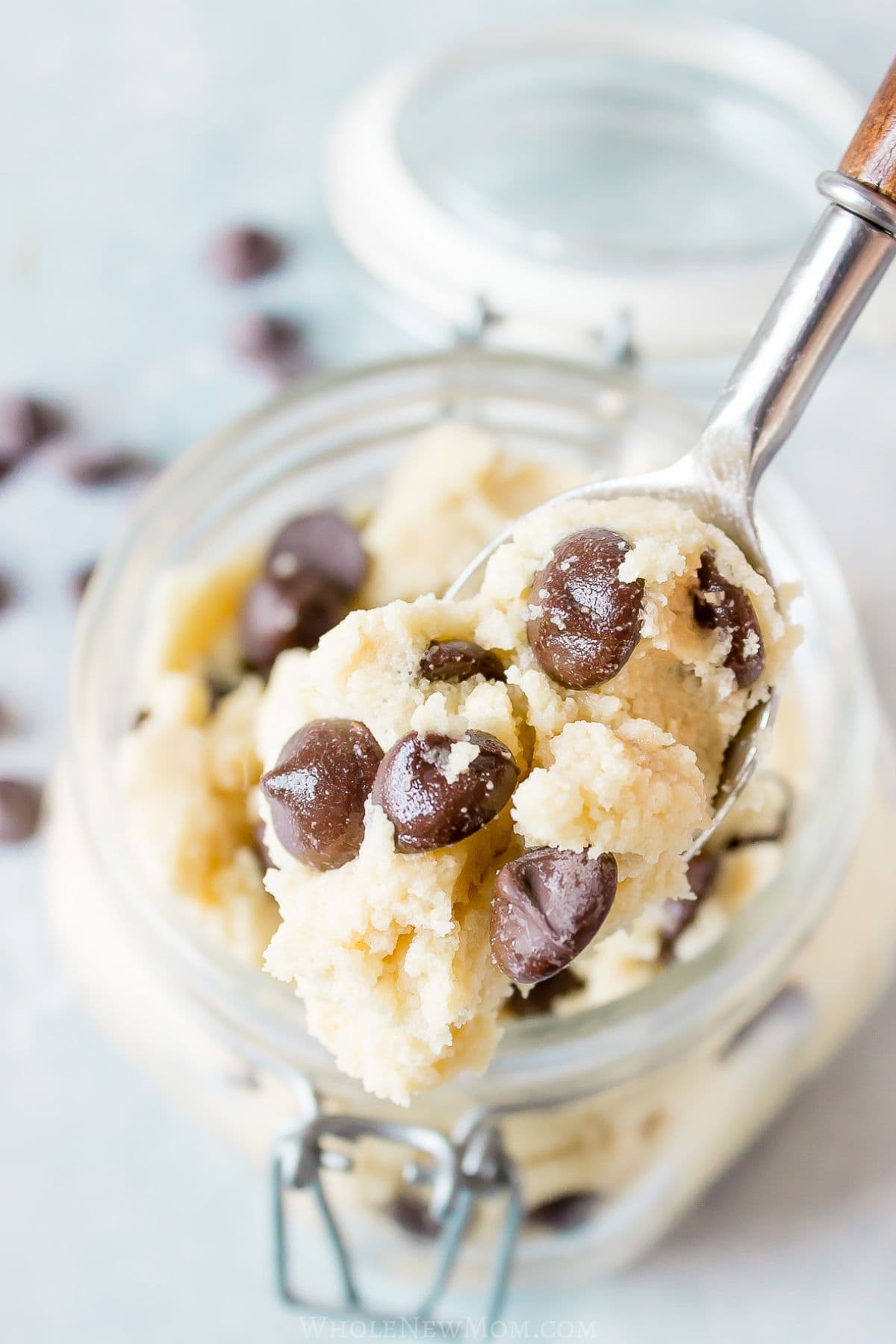 spoon holding sugar free cookie dough over mason jar of edible cookie dough.