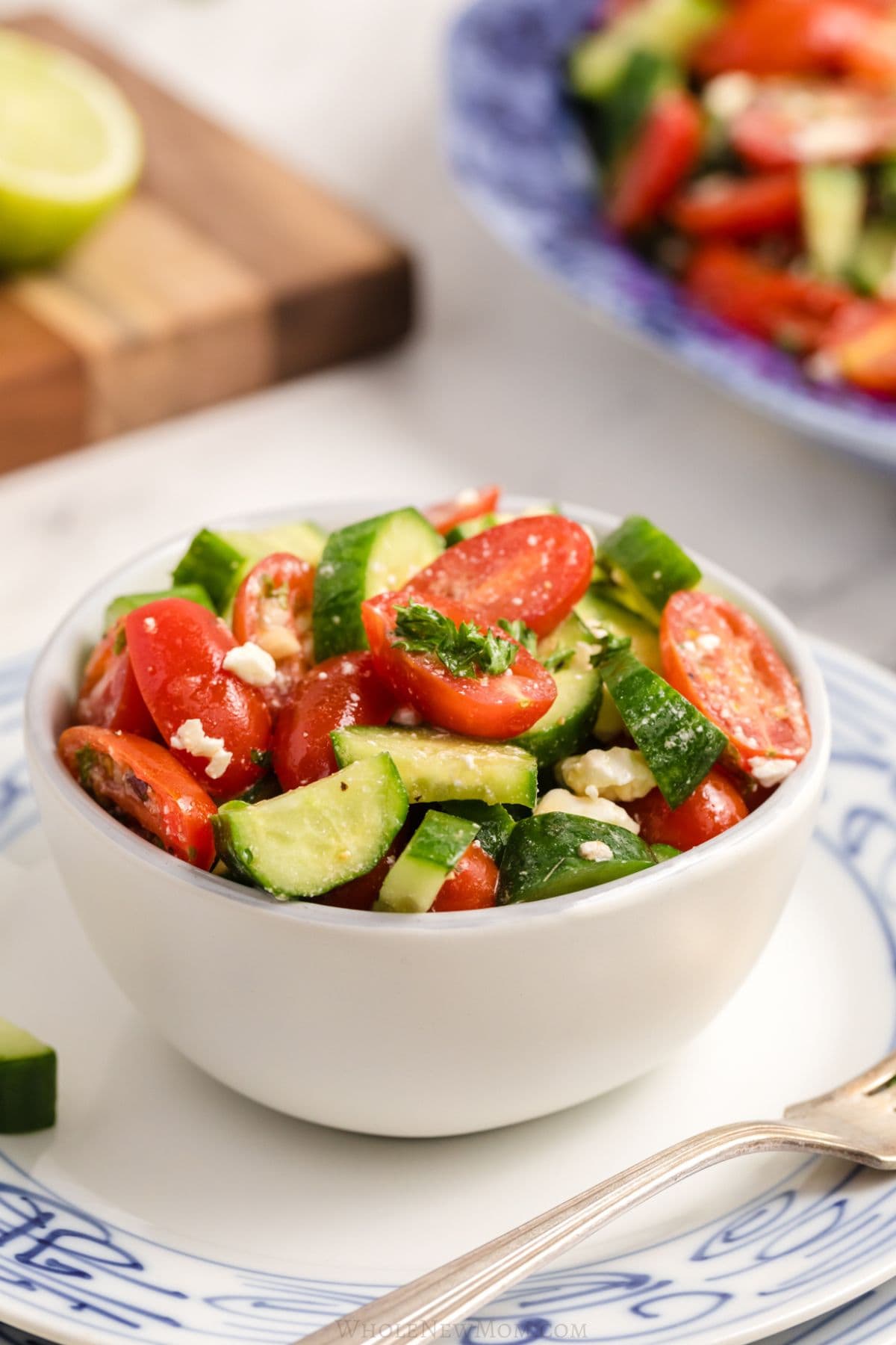 A white bowl filled salad, set on a blue and white plate.