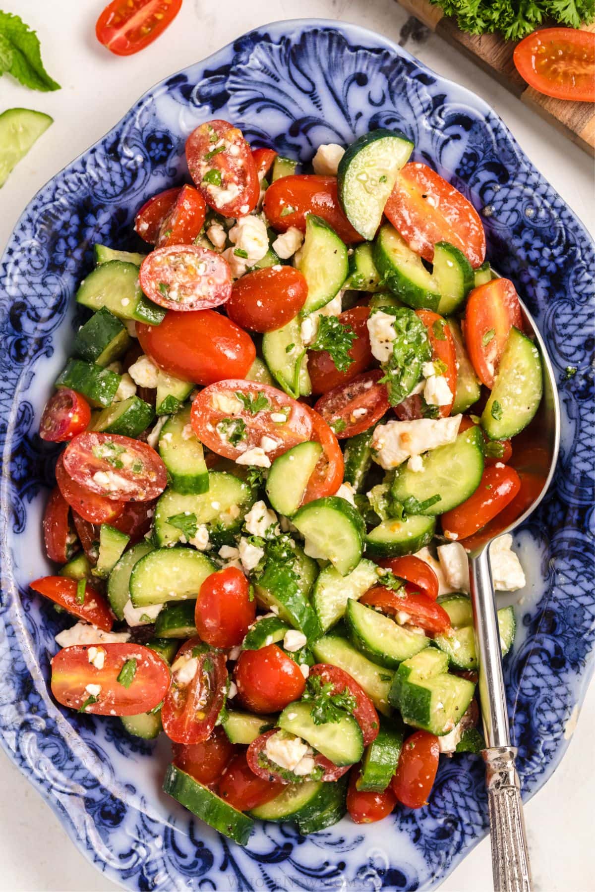 A serving dish filled with salad with a serving spoon resting inside.