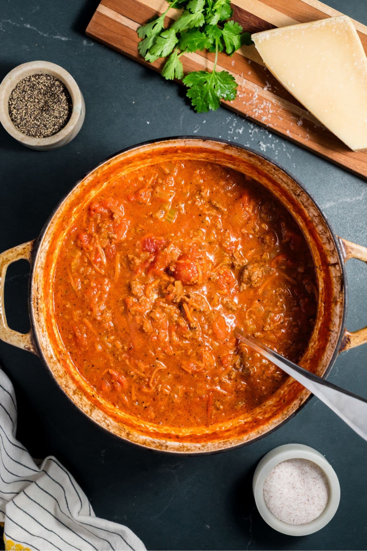Pot of beef bolognese sauce with ingredients nearby.